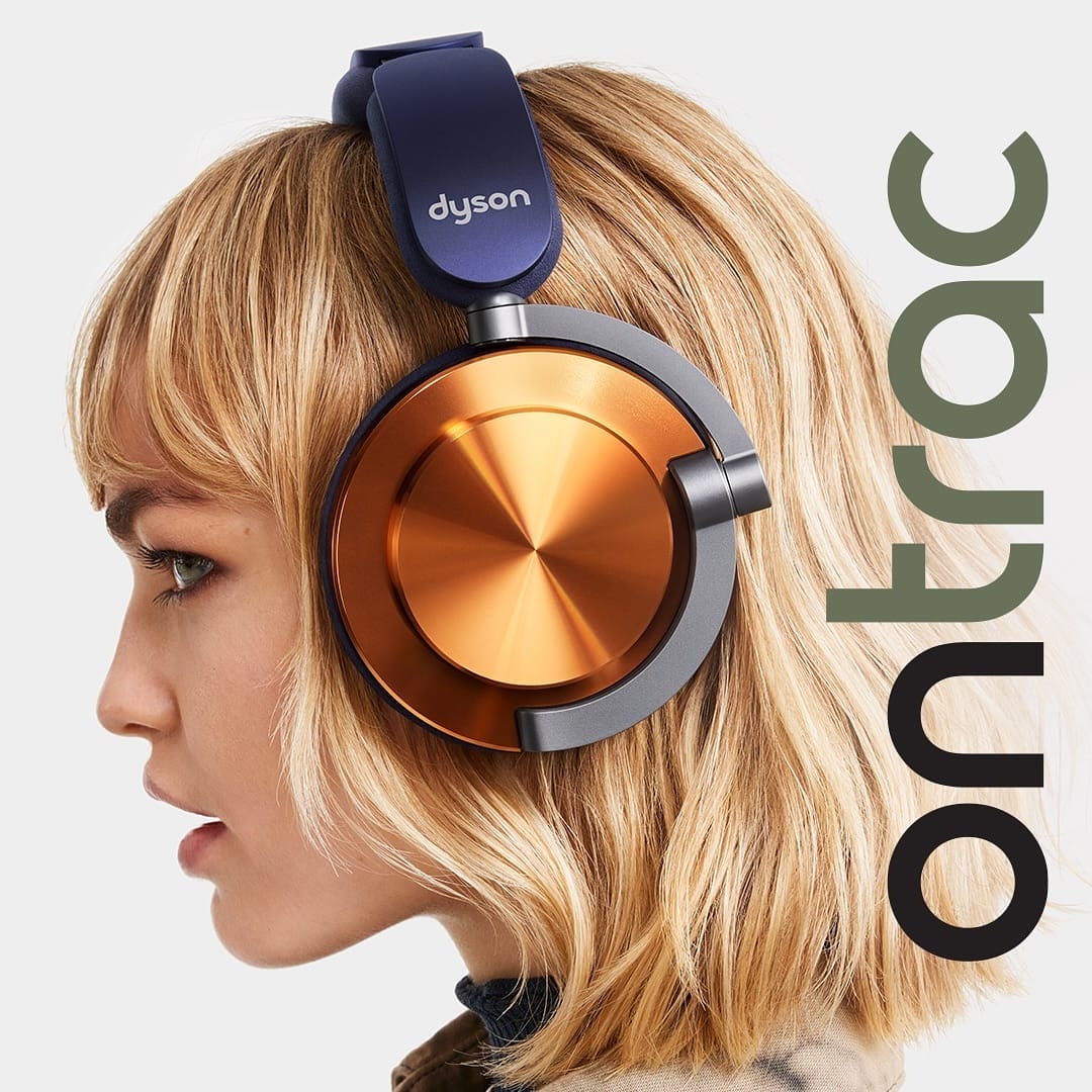 A woman wearing Dyson OnTrac headphones, with a close-up view highlighting the orange and blue design of the headphones.