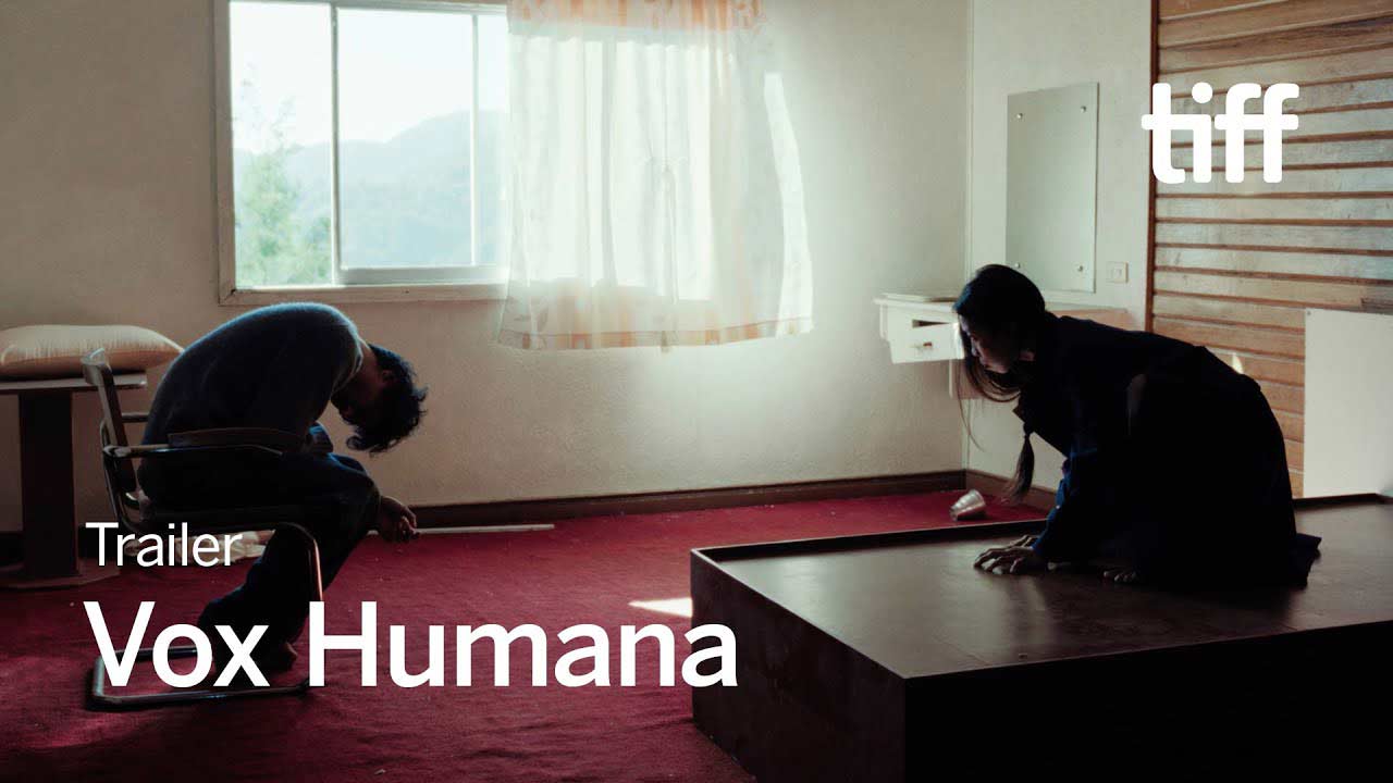In this still from Vox Humana, a man and woman appear isolated in a sparse room, each in a moment of reflection and emotional distance. The minimalist setting, combined with their physical postures, captures a mood of introspection and tension, setting the tone for the film’s exploration of human interconnectedness and existential questions.