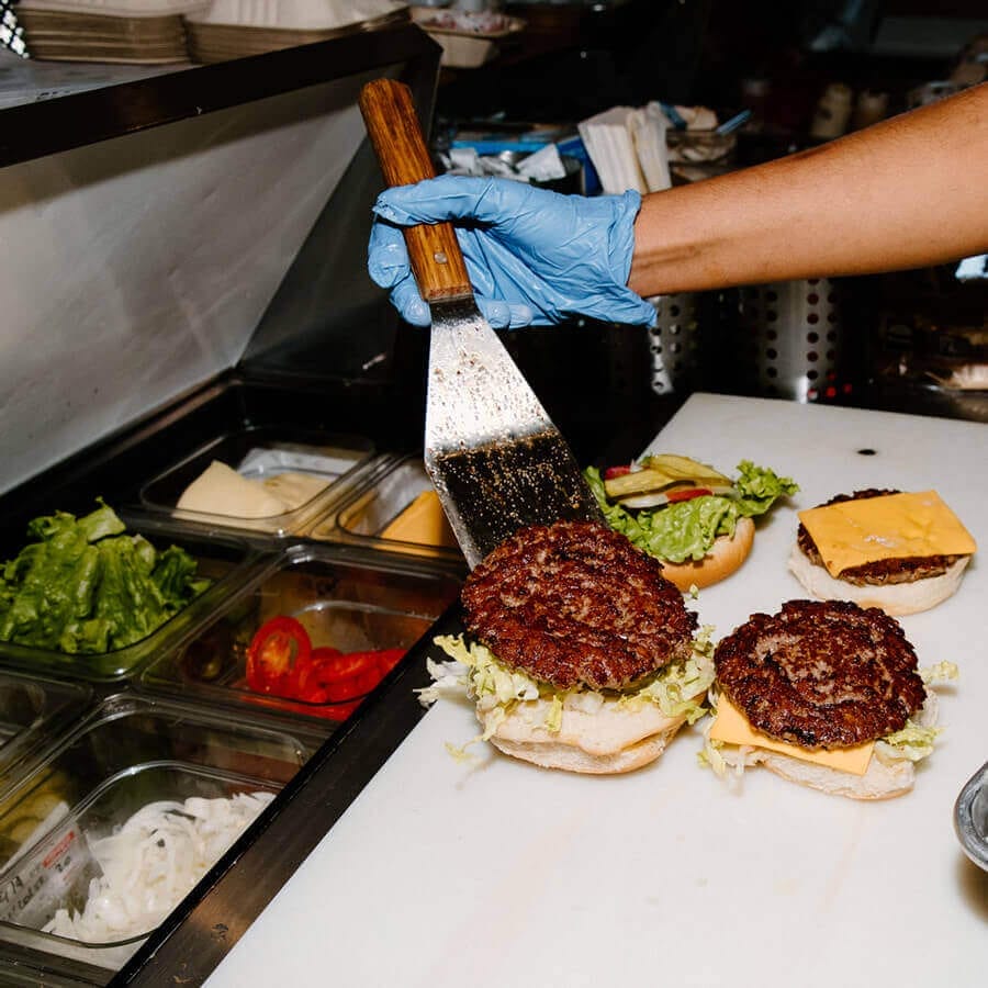 A burger being put together at the condiment bar.