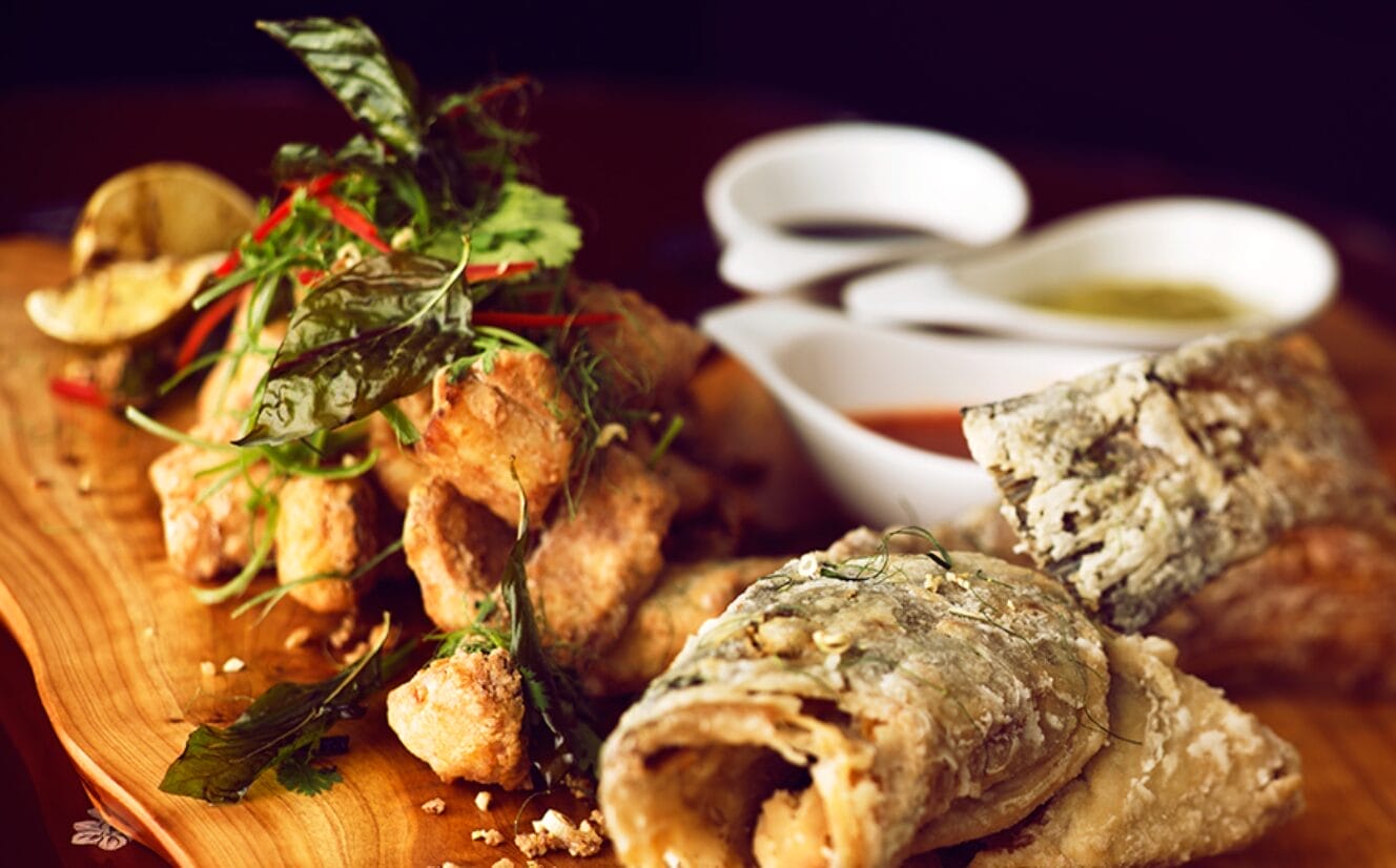 Crispy fried dish on a wooden serving board and dips on the side | Winterlicious 2025