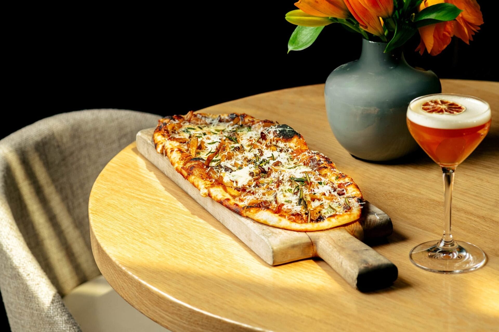 Pizza on a wooden serving board with a cocktail on the side | Winterlicious 2025