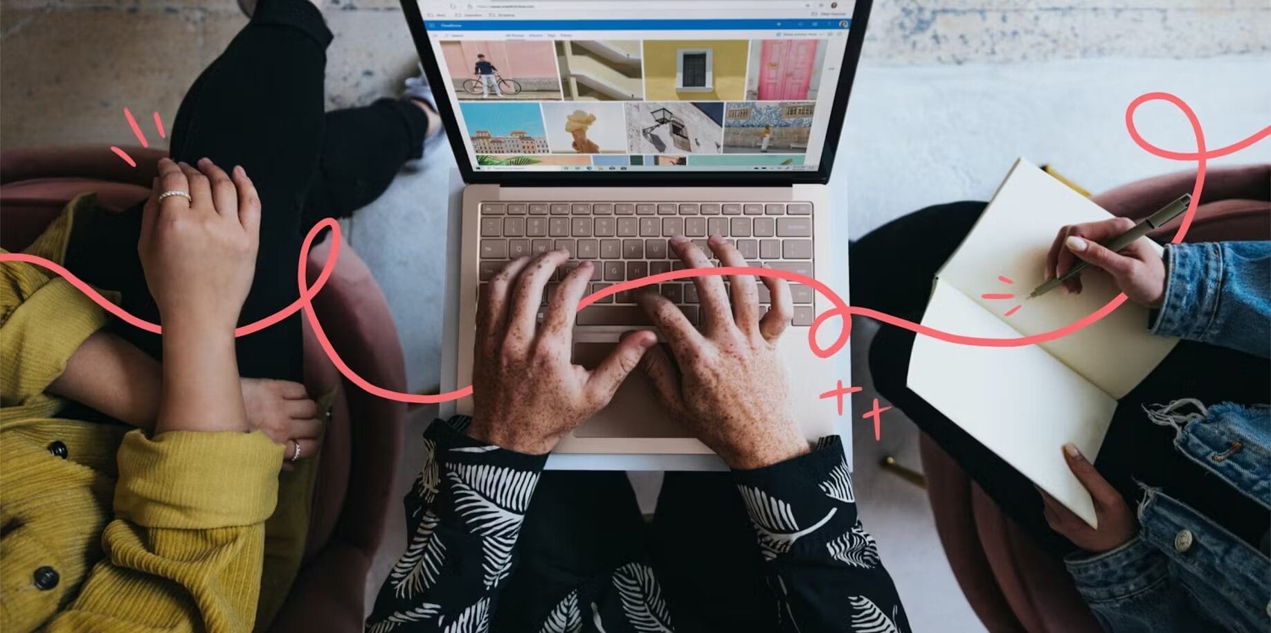 Overhead shot of three people collaborating, with one person typing on a laptop displaying an image gallery, another taking notes in a notebook, and the third resting their hands on their lap. A red, hand-drawn squiggly line flows across the image, adding a creative and dynamic visual element. | Engagement