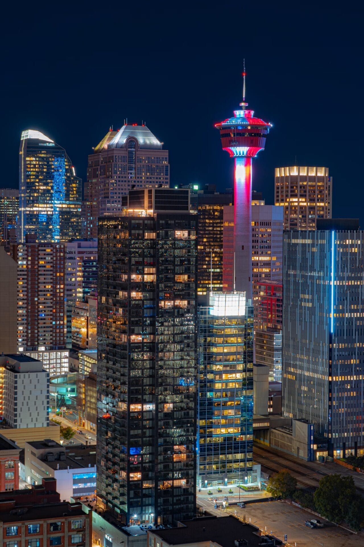 Calgary, Alberta skyline at night, featuring the illuminated Calgary Tower and surrounding high-rise buildings.