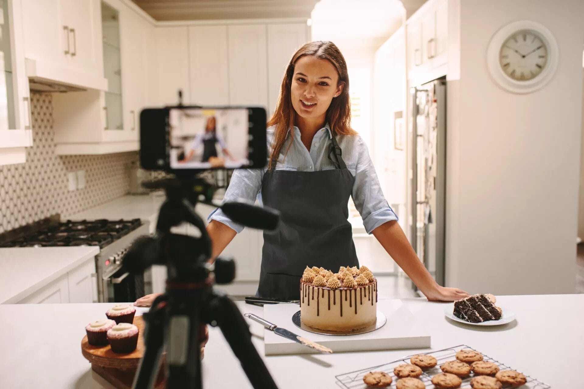 Content creator videoing in a kitchen with cake on the counter