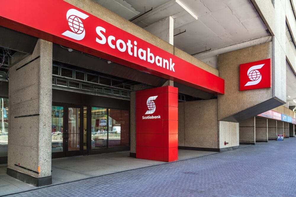A Scotiabank branch with a bold red sign featuring the bank's name and logo, located in an urban setting with glass doors and a modern exterior.