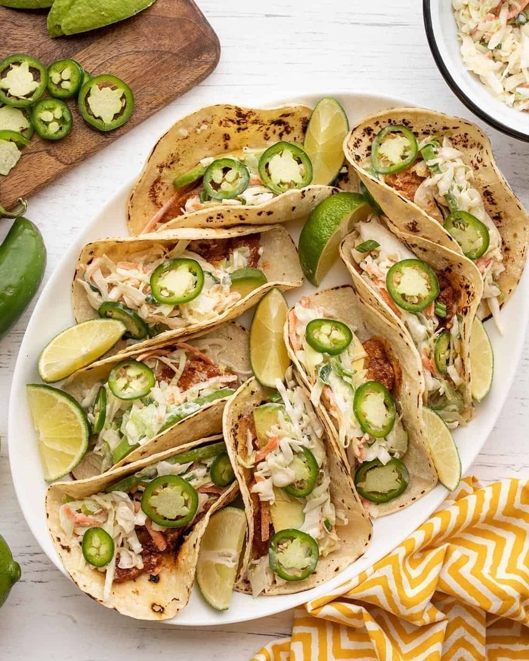 Fish tacos with lime slaw served in soft tortillas, topped with fresh cabbage and lime wedges