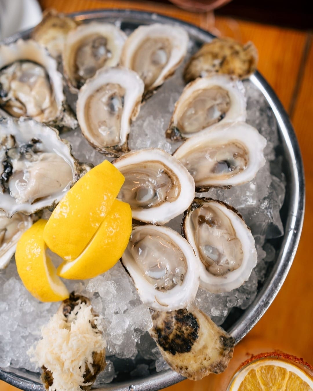 A tray of fresh oysters on ice garnished with lemon wedges, served at a summer patio in Toronto’s Distillery Historic District