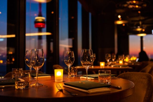Elegant restaurant table with wine glasses and a panoramic view of the city, perfect for Summerlicious 2025 dining in Toronto.