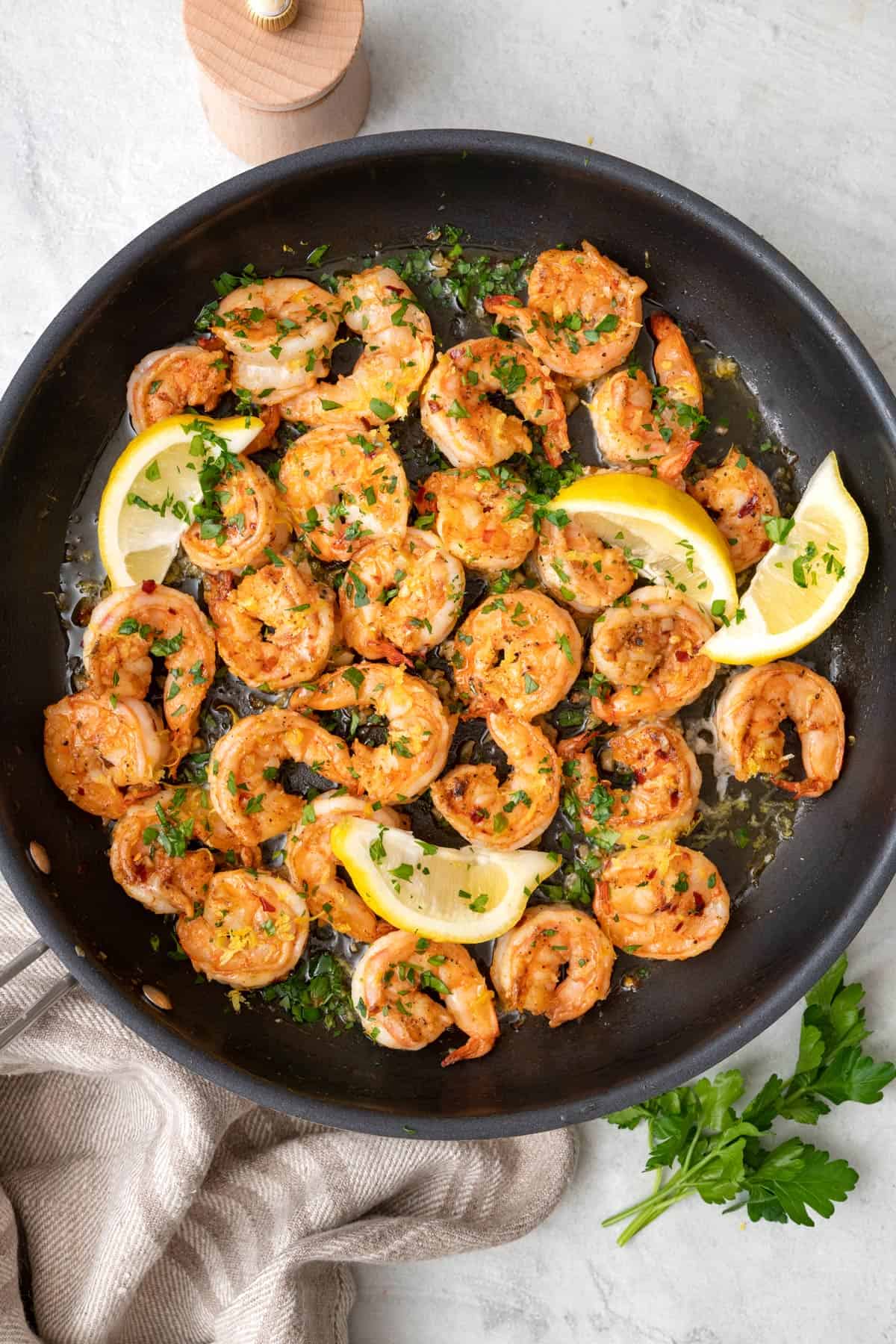 Seasoned shrimp and lemon on a skillet.