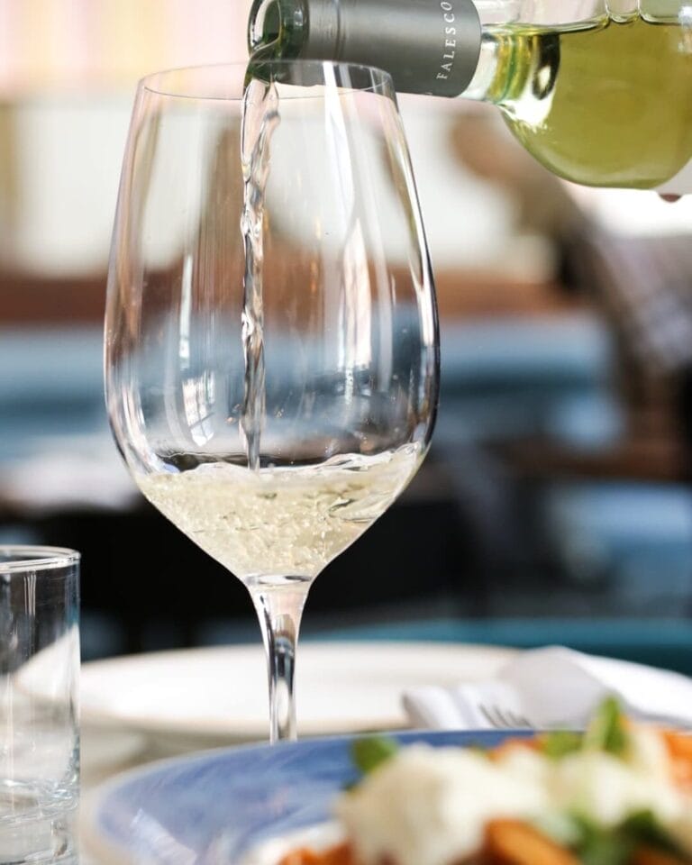 White wine bottle pouring into a wine glass.