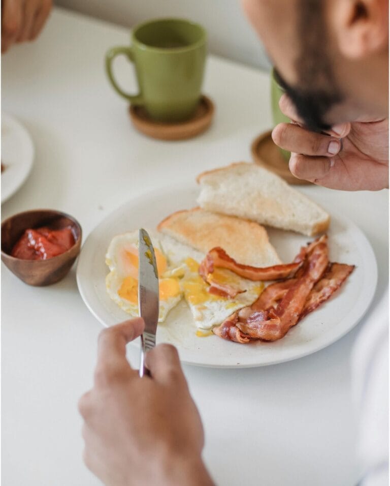 man having bacon and egg breakfast