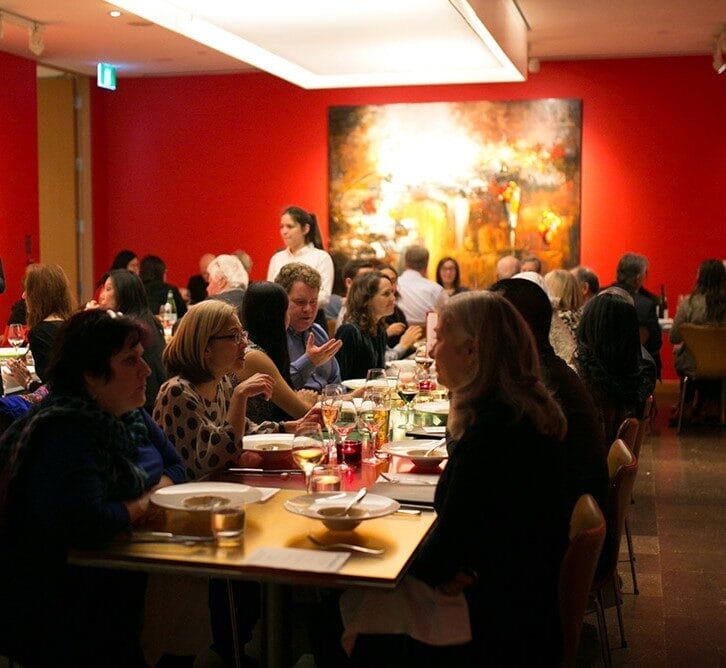 people dining at ago pistro with aet piece in the background