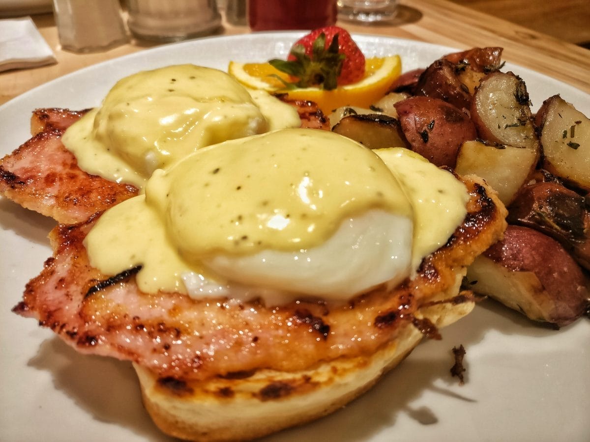 egg benny plated with potato and fruits