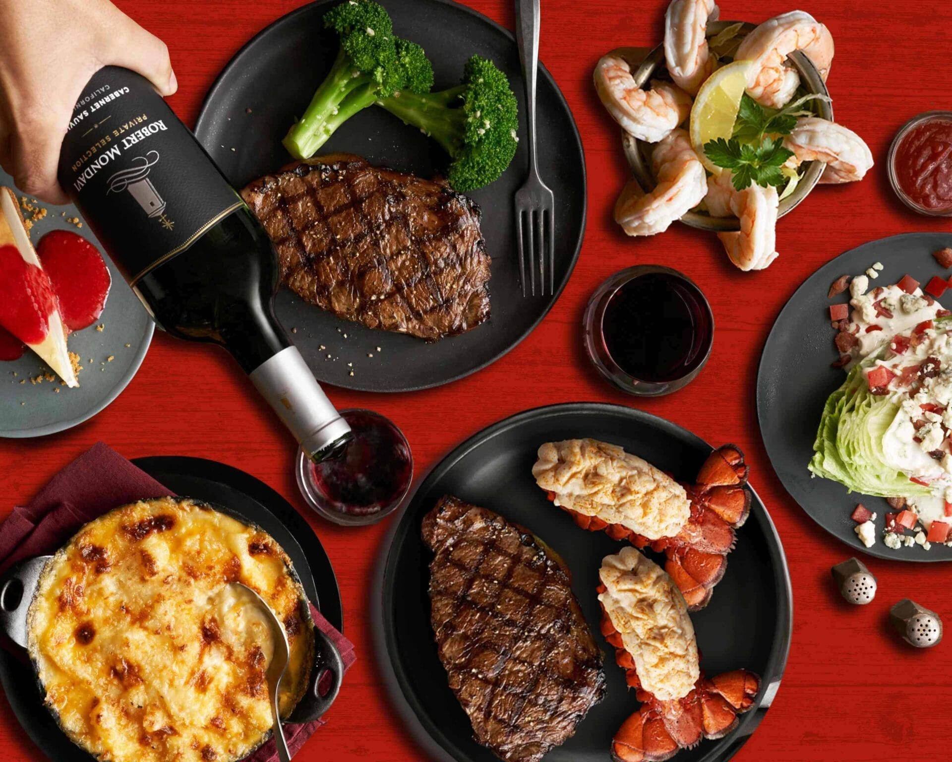 picture of steak dinenr served with wine, lobster tails, salad, cheesecake etc
