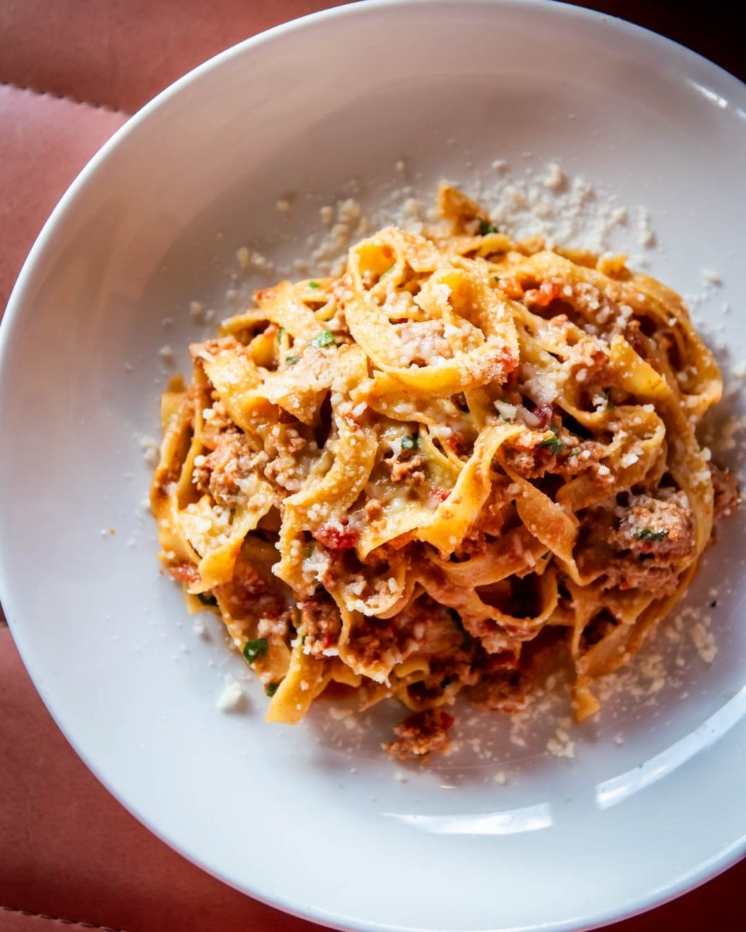 A plate of pasta topped with meat and melted cheese, garnished with herbs, is a must-try restaurant for Summerlicious 2025 in Toronto.