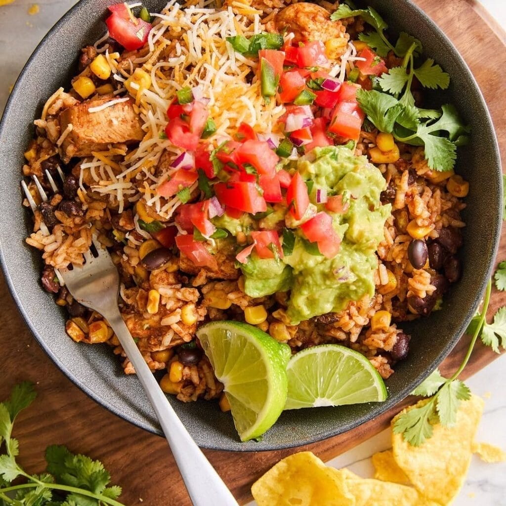 Chicken burrito bowl with rice, beans, corn, guacamole, fresh salsa, and lime for a flavorful Father’s Day meal.