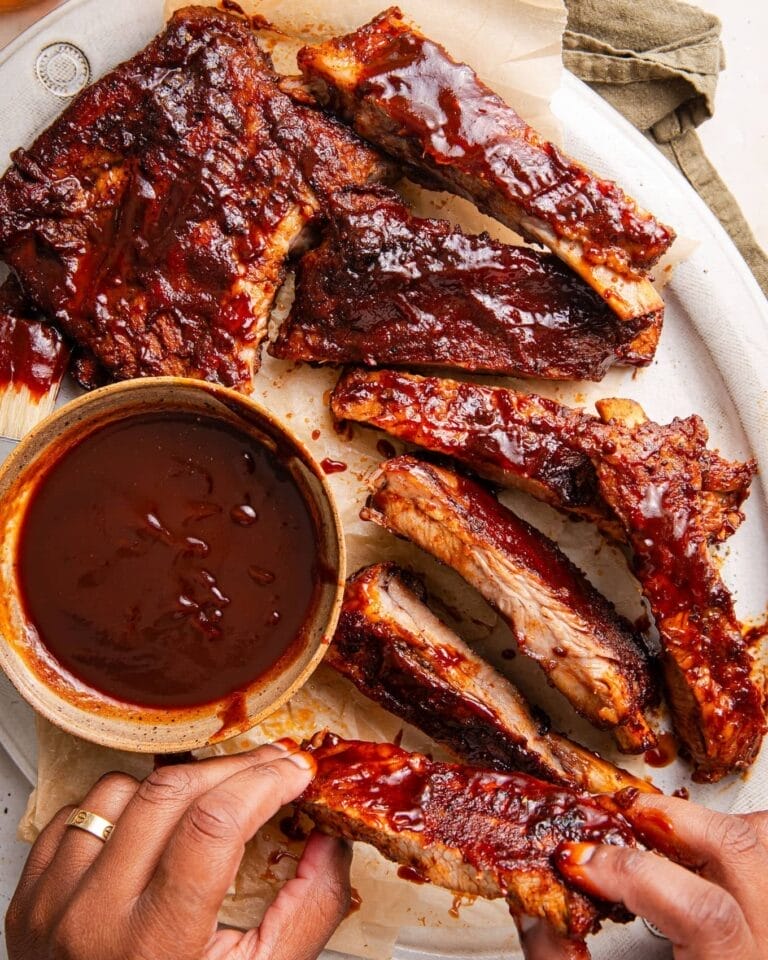 Juicy, saucy BBQ ribs ready for Father’s Day lunch and dinner recipes, displayed on a platter with a side of tangy BBQ sauce for dipping.