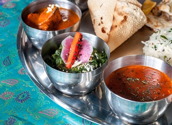 Best South Asian street food in Toronto featuring Indian Street Food Company thali with curries, naan, rice, and chutneys.