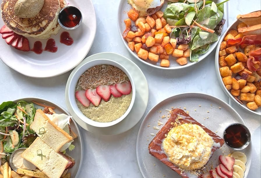 Brunch spread with pancakes, eggs, and breakfast plates at Sisters & Co in Toronto