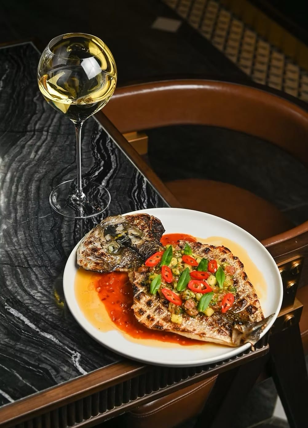 Grilled whole fish and wine served at Petite Lune, a modern Vietnamese restaurant and one of the best new restaurants in Toronto 2026.