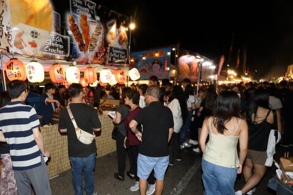 People waiting in lines for Taste of Asia at night.