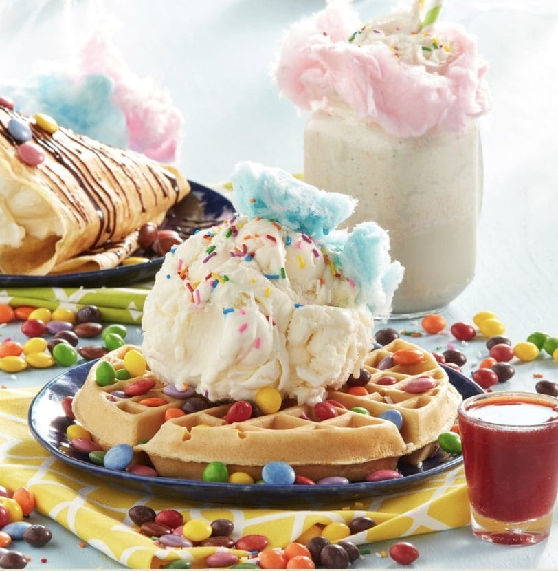 D Spot Dessert Cafe waffle topped with ice cream, cotton candy, sprinkles, candy pieces, chocolate drizzle, and a milkshake.