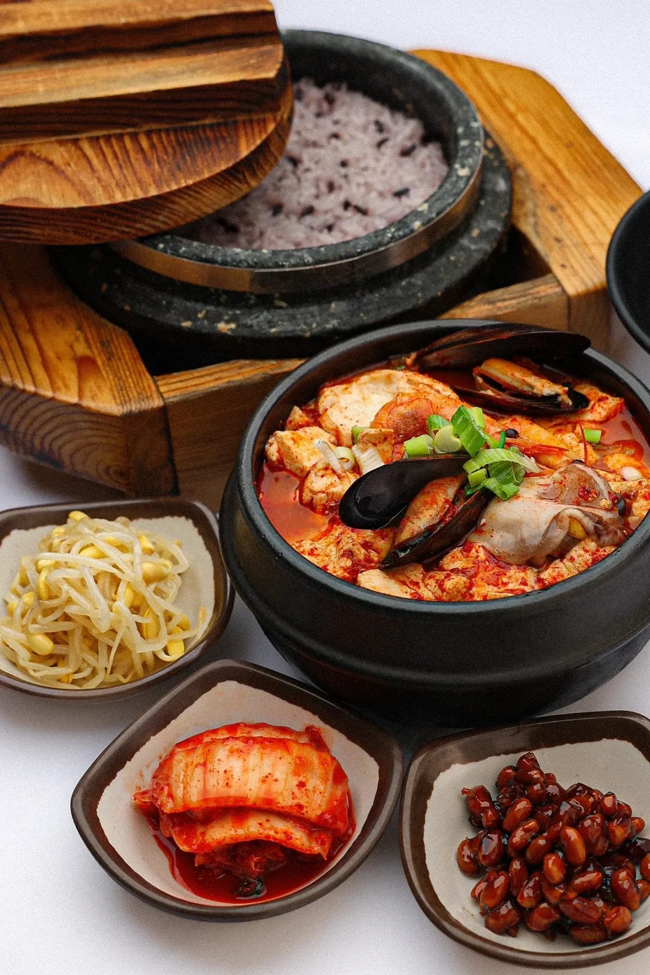 Seafood soon tofu stew served with purple rice, kimchi, bean sprouts, and glazed beans at Buk Chang Dong Soon Tofu.