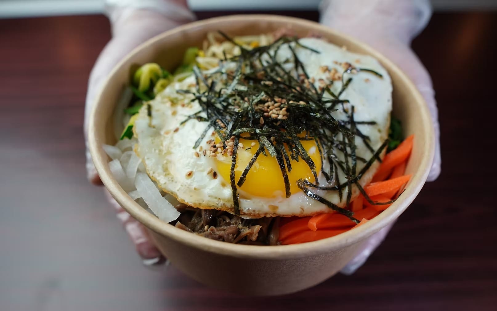 Bibimbap bowl with fried egg, seaweed, sesame seeds, vegetables, and rice at Korean Village Restaurant.